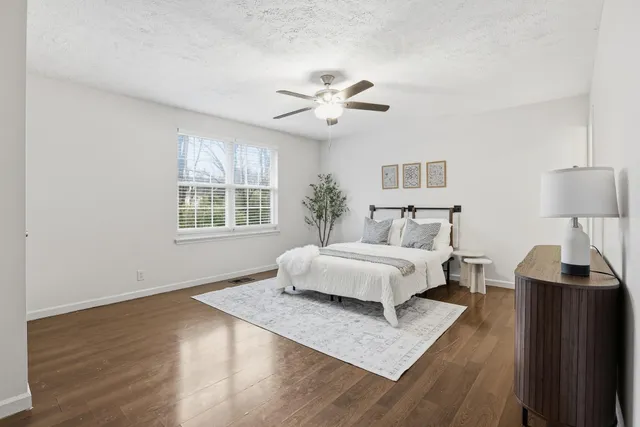 a spacious bedroom with a bed and wooden floor