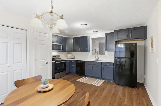 a kitchen with stainless steel appliances granite countertop a sink a stove a refrigerator cabinets and a dining table