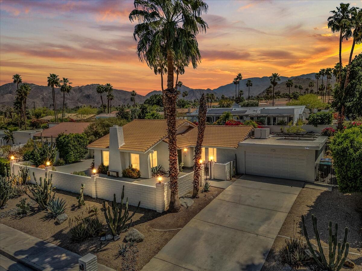 a front view of a house with a garden and lake view