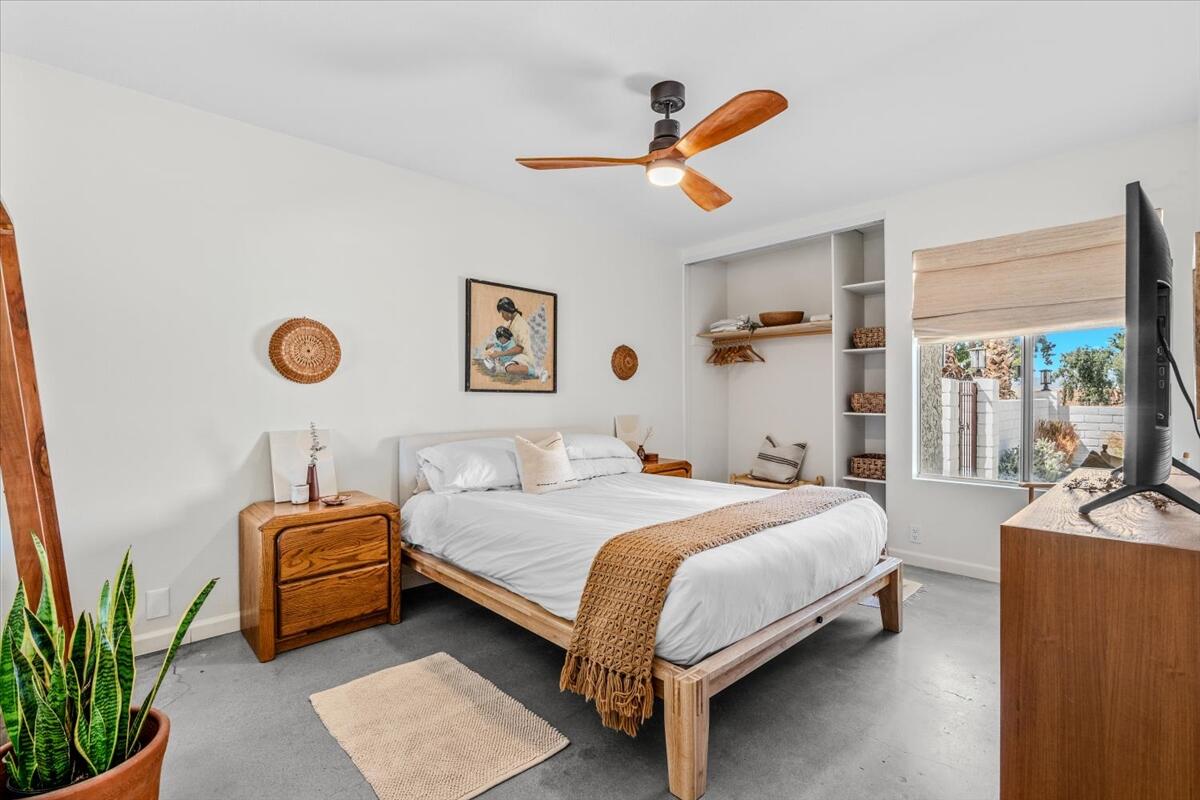 73149 Haystack Road Palm Desert, CA 92260 - Photo 24 of 32 a bedroom with a bed a couch and a chandelier