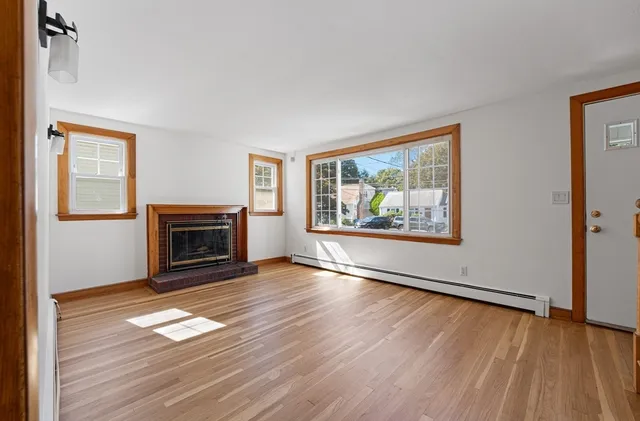 a view of empty room with wooden floor and fireplace