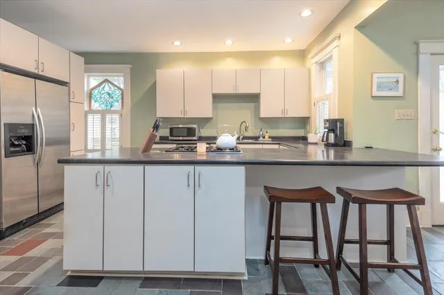 a kitchen with stainless steel appliances granite countertop a table chairs sink and cabinets