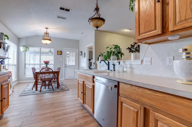 a kitchen with stainless steel appliances kitchen island granite countertop a table chairs in it and wooden floors
