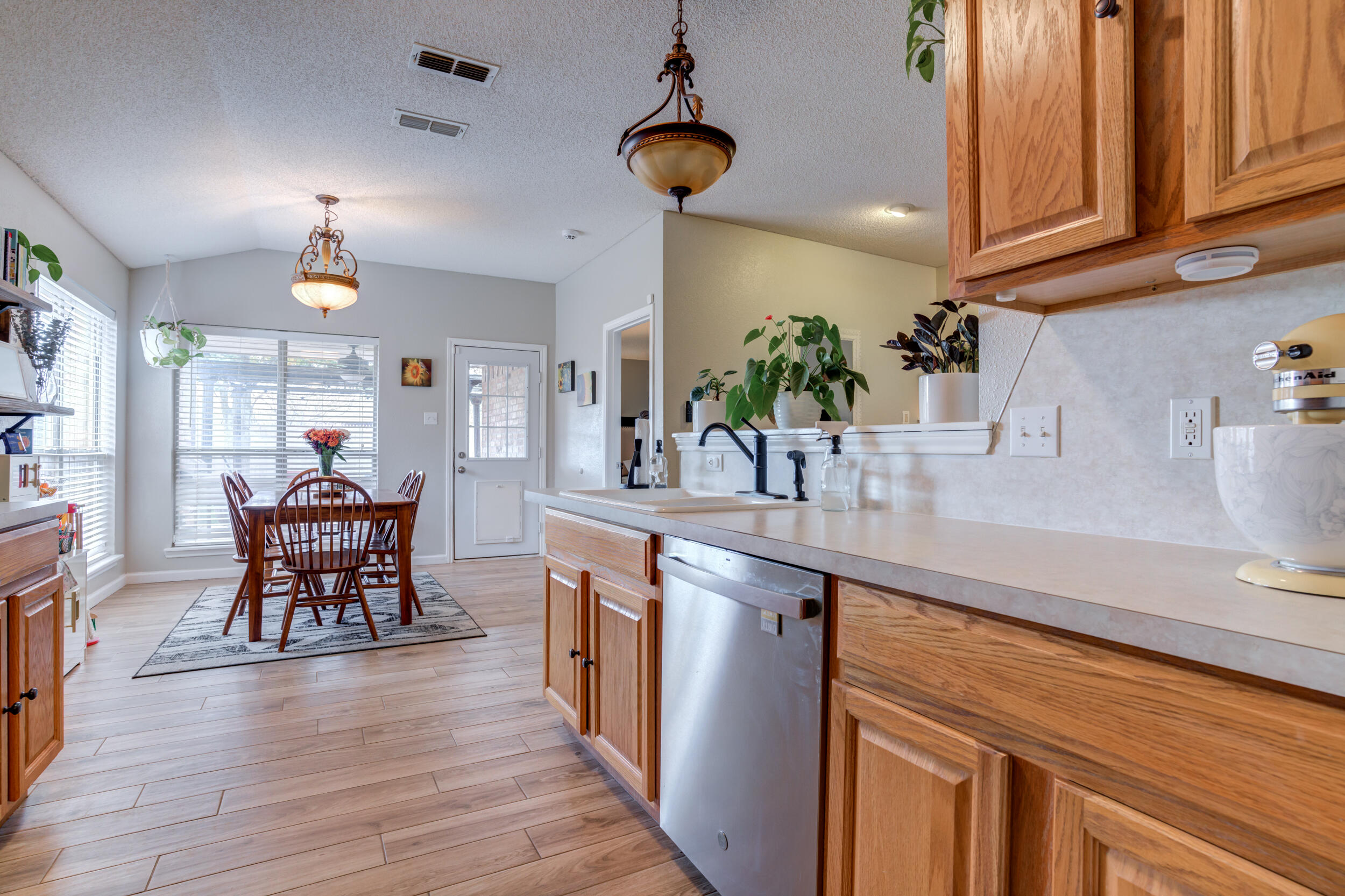 1607 79th Street Lubbock, TX 79423 - Photo 23 of 53 a kitchen with stainless steel appliances kitchen island granite countertop a table chairs in it and wooden floors
