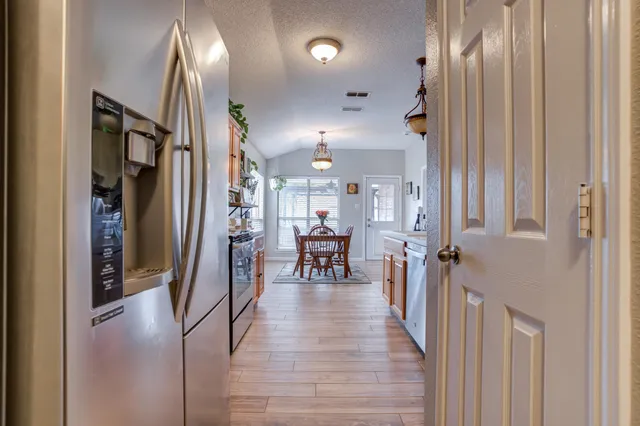 a view of a hallway with dining area wooden floor and a chandelier