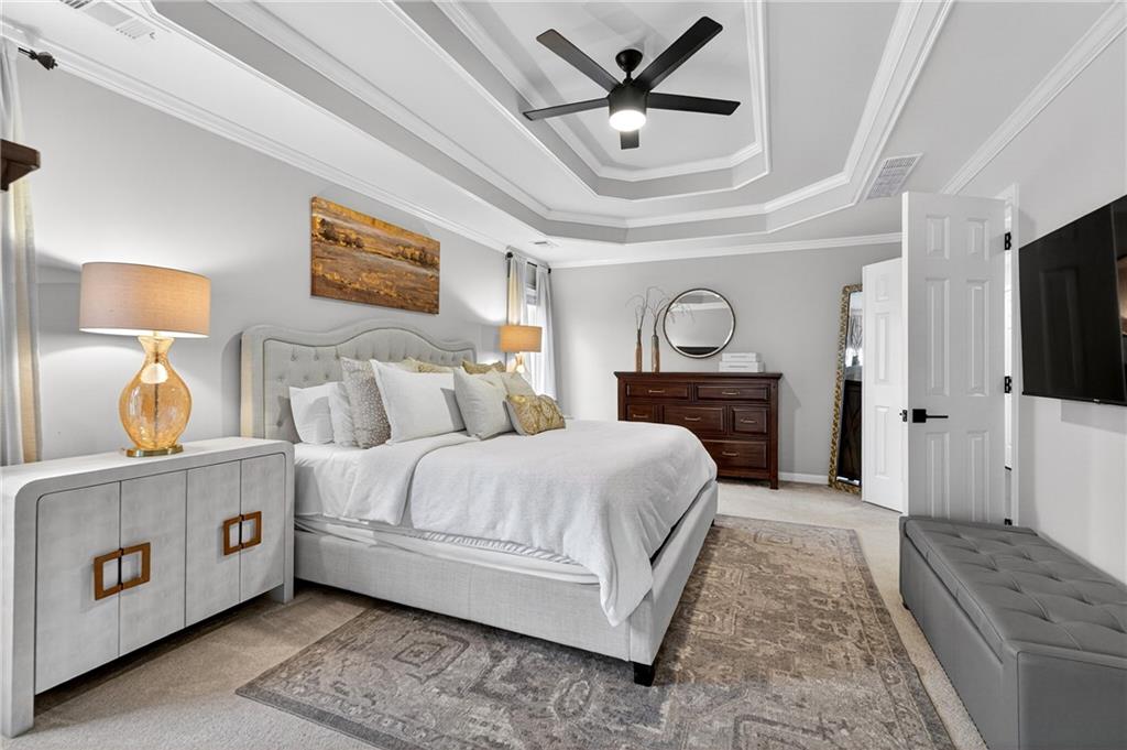 14325 Morning Mountain Way Milton, GA 30004 - Photo 27 of 66 a spacious bedroom with a bed a mirror on dresser and a chandelier