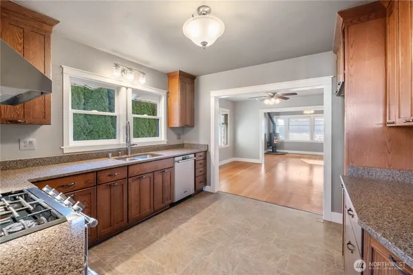 a large kitchen with kitchen island a large window a sink stainless steel appliances and cabinets