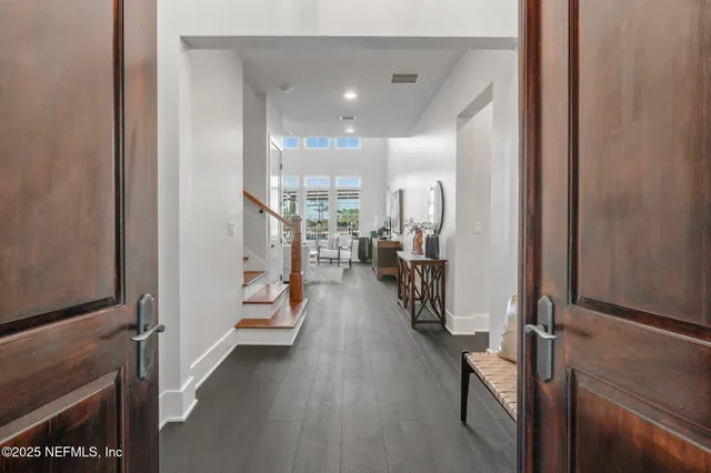 a living room with couches a coffee table and kitchen view with wooden floor