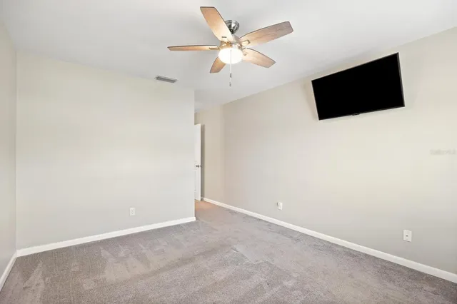an empty room with a flat screen tv and a ceiling fan