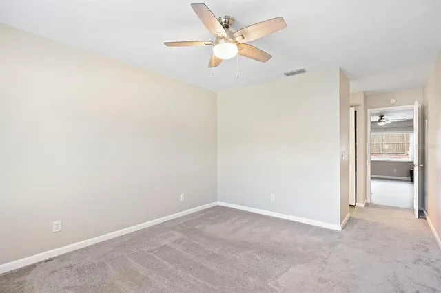an empty room with a ceiling fan and a window