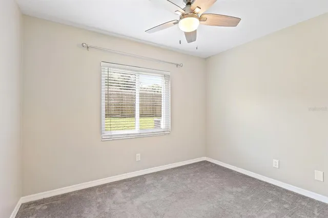 an empty room with a window and a fan