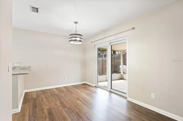 an empty room with wooden floor mirror and windows