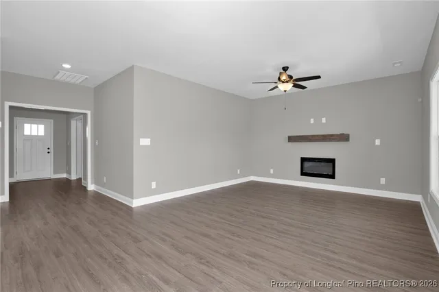 a view of an empty room with wooden floor and a fireplace