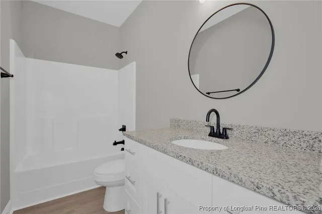 a bathroom with a granite countertop sink mirror vanity and toilet