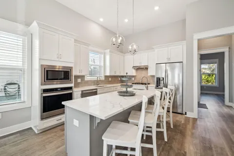 a kitchen with a refrigerator a stove top oven a sink dishwasher and white cabinets with wooden floor