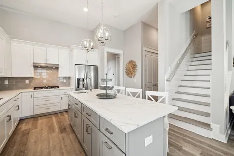 a kitchen with cabinets a sink dishwasher a stove and white cabinets with wooden floor