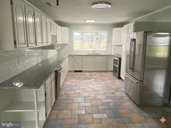 a kitchen with stainless steel appliances granite countertop a refrigerator and a sink