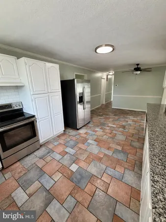 a view of a refrigerator in kitchen and empty room with wooden floor