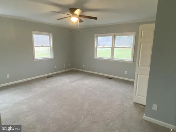 an empty room with a window and a fan