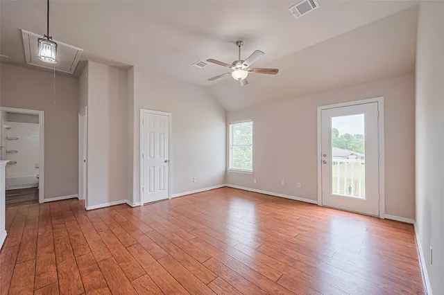 a view of empty room with wooden floor and fan