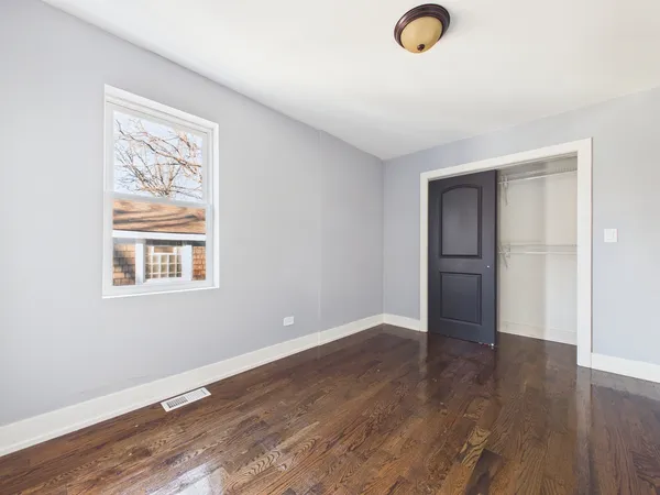 a view of an empty room with wooden floor and windows