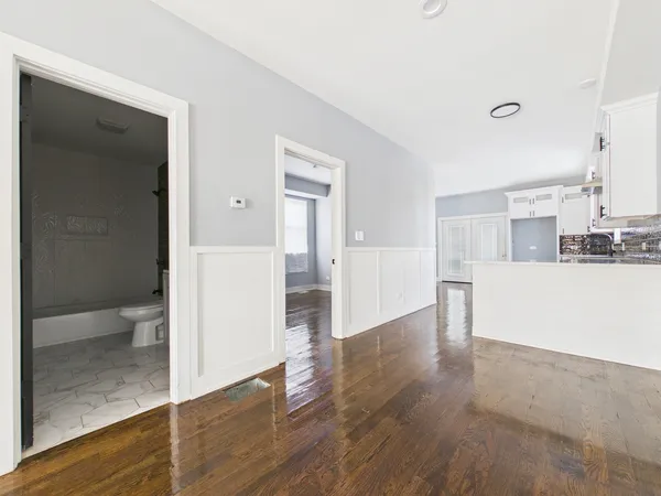 a view of an empty room with wooden floor and a closet