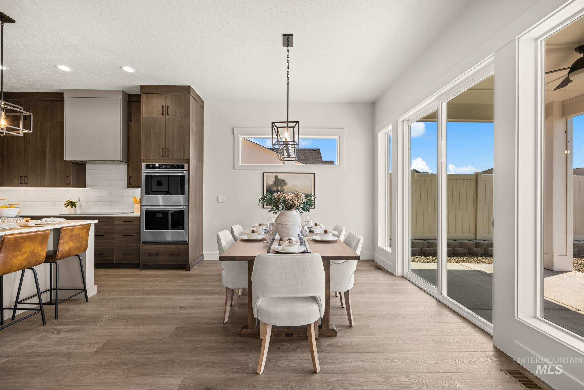 345 South Strut Way Boise, ID 83716 - Photo 13 of 50 Open-concept kitchen and dining area featuring wood-finish flooring, custom cabinetry, stainless steel double ovens, and a kitchen island with stone countertops