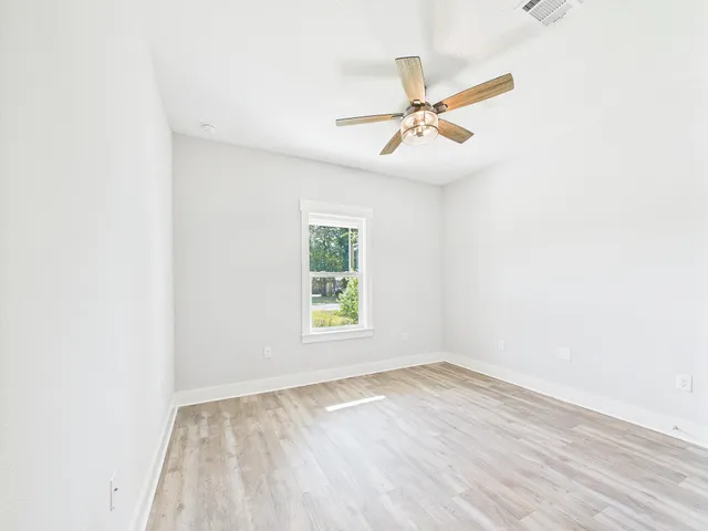an empty room with a ceiling fan and wooden floor
