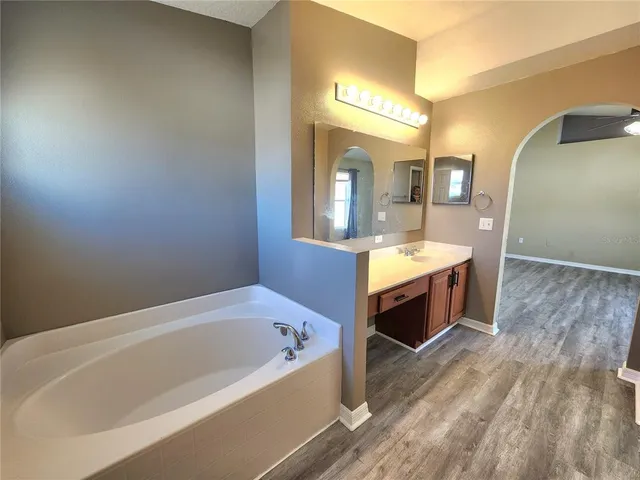 a spacious bathroom with a tub sink and mirror