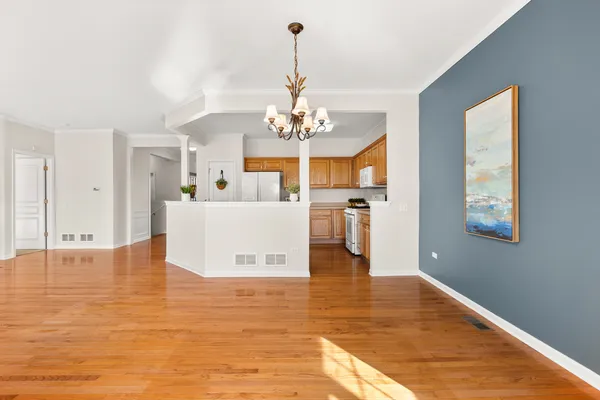 a kitchen with kitchen island a stove a chandelier and a view of living room