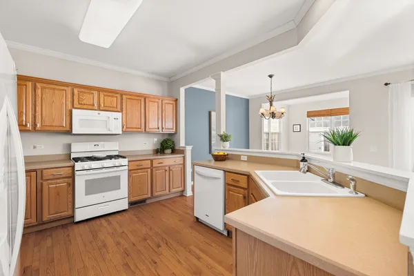 a kitchen with stainless steel appliances granite countertop a refrigerator a sink dishwasher a stove and white countertops with wooden floor