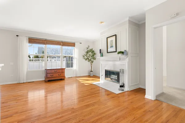 a view of an empty room with wooden floor fireplace and a window