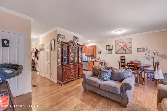 a living room with furniture kitchen view and a wooden floor