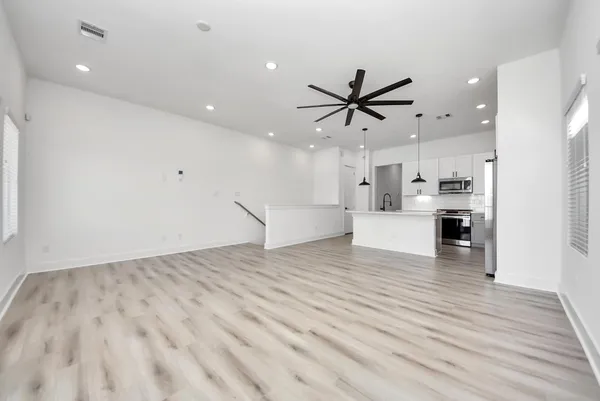 a view of kitchen and empty room with wooden floor