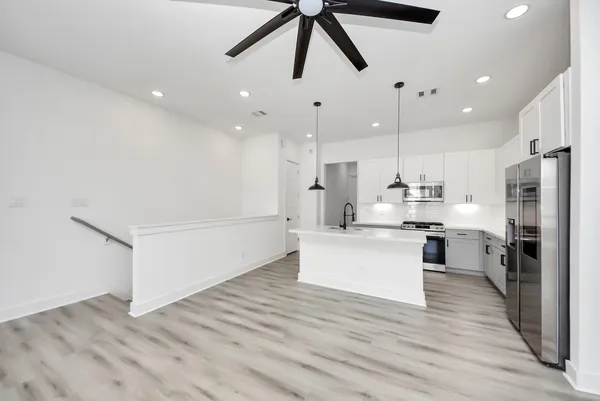 a kitchen with stainless steel appliances kitchen island hardwood floor sink and stove