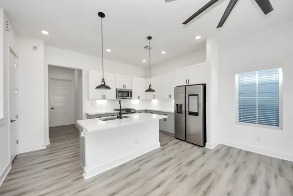 a kitchen with stainless steel appliances granite countertop a refrigerator a sink dishwasher and a oven with white cabinets