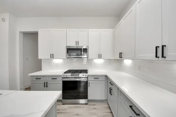 a kitchen with stainless steel appliances a sink stove and white cabinets