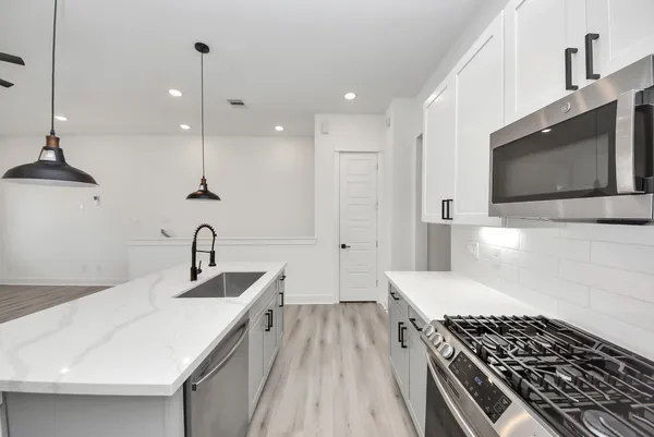 a kitchen with kitchen island stainless steel appliances a sink a stove and a center island