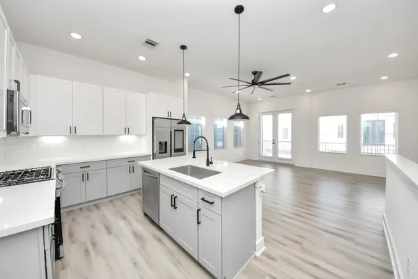 a kitchen with a sink stove cabinets and wooden floor