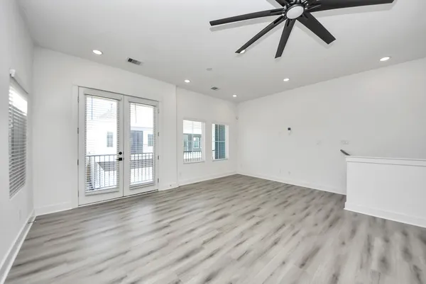a view of an empty room with window and wooden floor