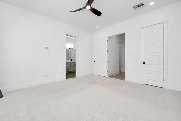 an empty room with ceiling fan and windows