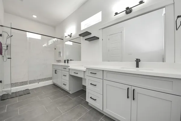 a spacious bathroom with a double vanity sink a mirror a shower and vanity