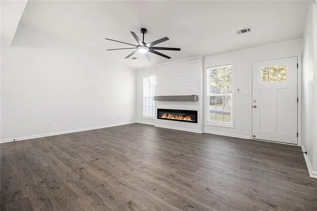 a view of a livingroom with a hardwood floor a ceiling fan and a window