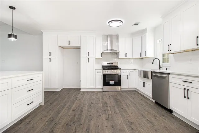 a kitchen with stainless steel appliances white cabinets and wooden floors