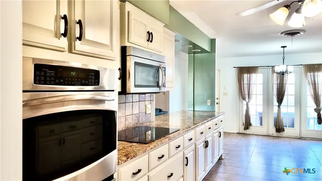 a view of an empty room with window and a kitchen