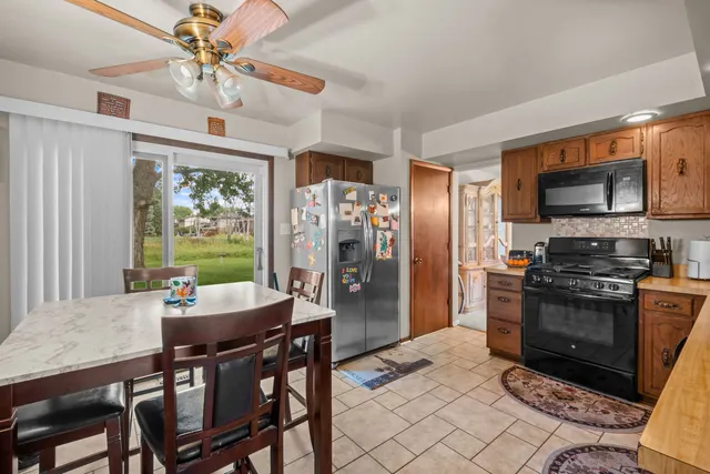 a kitchen with stainless steel appliances granite countertop a stove a refrigerator a kitchen island a dining table and chairs with wooden floor