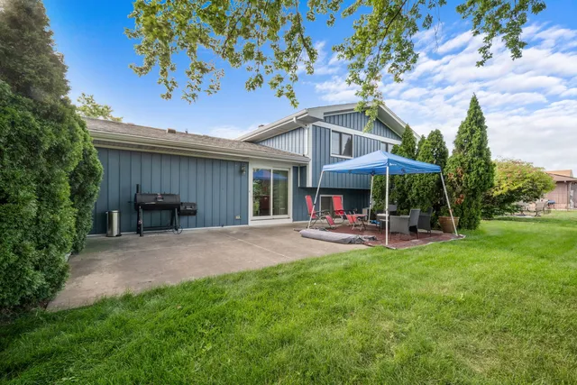 a front view of a house with table and chairs under an umbrella