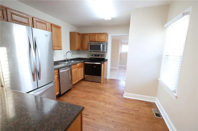 a kitchen with stainless steel appliances granite countertop a refrigerator a stove and a sink