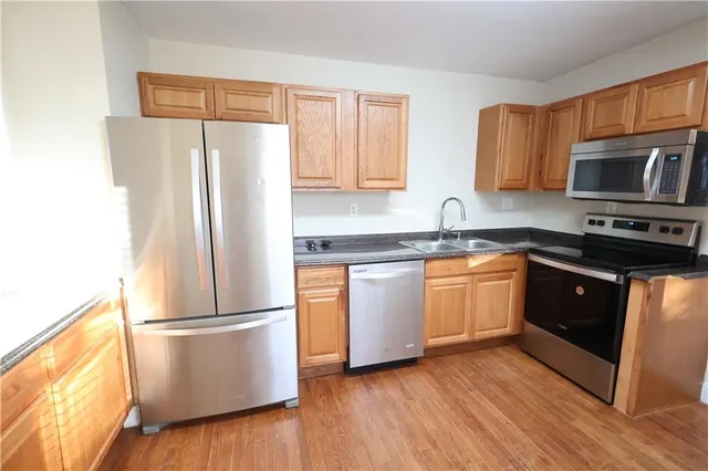 a kitchen with a refrigerator sink and wooden cabinets