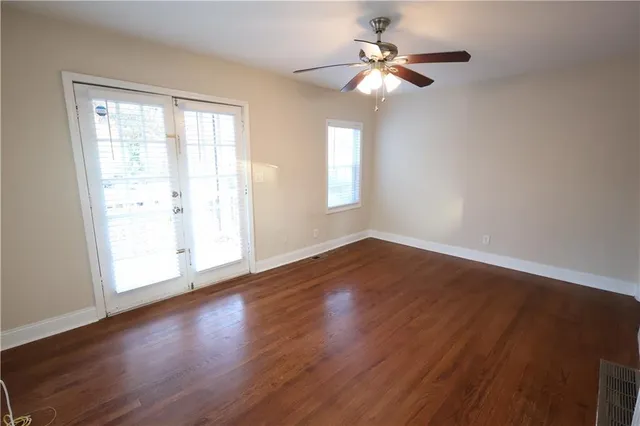 a view of an empty room with wooden floor and a window